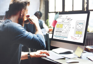 Man drinking coffee and looking at website design outline.