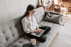 A woman sitting on a couch, using her computer