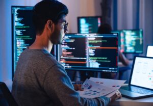 man with glasses programming and designing software
