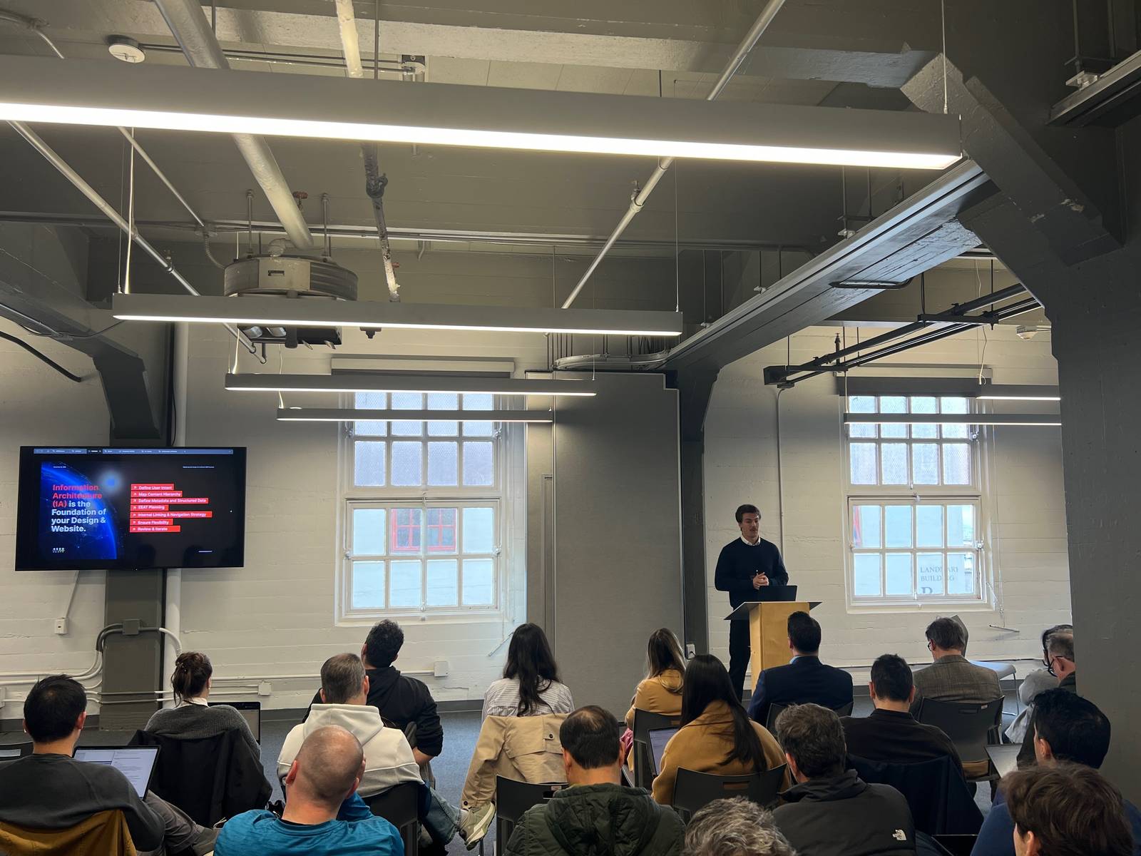 Ben Gunther presenting at the GEO Conference in San Francisco, slide showing information architecture as the foundation of site design