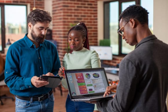 A digital marketing team reviewing store performance dashboards on a laptop and tablet