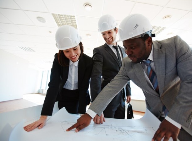 Project team in hard hats reviewing construction drawings together